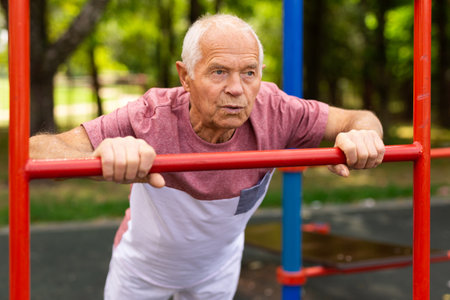 Old man in sportswear exercising push-ups outdoorsの写真素材
