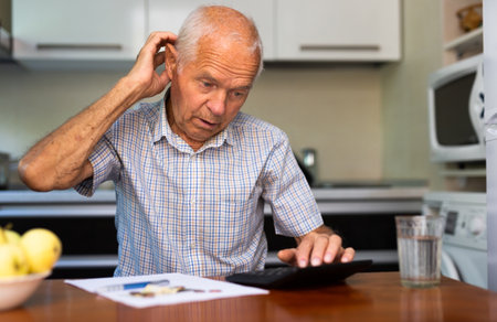 Elderly man counts money at the tableの写真素材