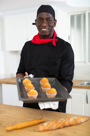 Portrait of positive chef with just baked hot cupcakesの写真素材