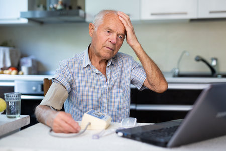 Modern elderly man sit at home having online consultation with doctor on computer, sick senior male talk on video call consulting using laptop. Healthcare conceptの写真素材