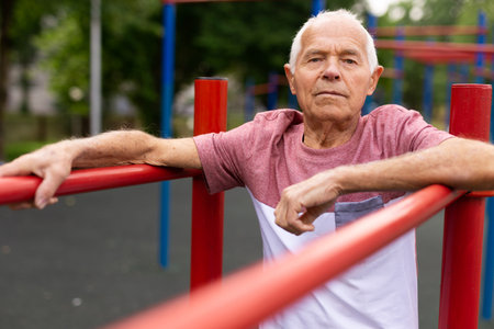 Old man standing between parallel bars outdoorsの写真素材