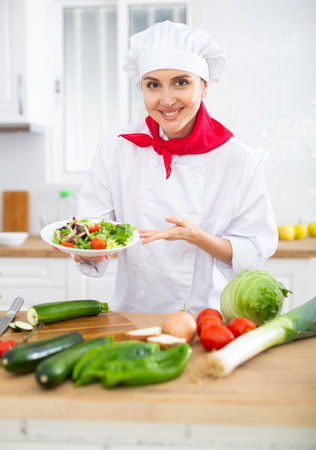 Female chef demonstrating excellent salad in the kitchenの写真素材