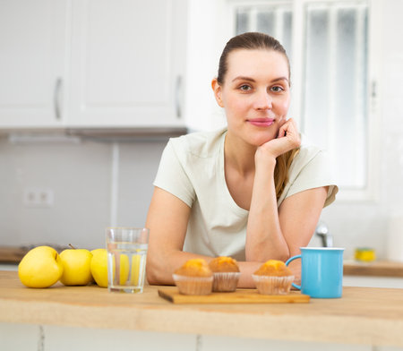 Positive woman having breakfast, drinking coffeeの写真素材