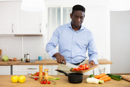 Man standing in kitchen cutting vegetables for saladの写真素材