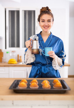 Woman holding mug of fresh coffee and muffins, having hot drink for breakfastの写真素材
