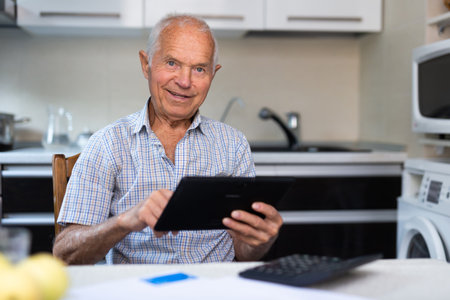 Senior man with tablet making purchases at homeの写真素材