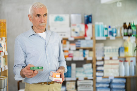 Elderly man chooses pills at pharmacyの写真素材