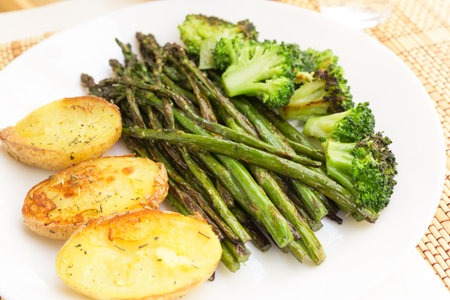 lean dish of cooked fried inflorescences of broccoli, asparagus growth and baked potatoes and Provencal herbsの写真素材