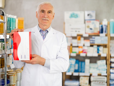 Elderly male pharmacist offers box with medical deviceの写真素材