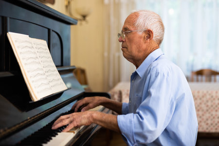 Man practicing playing piano in the living room of his home after retirement from workの写真素材