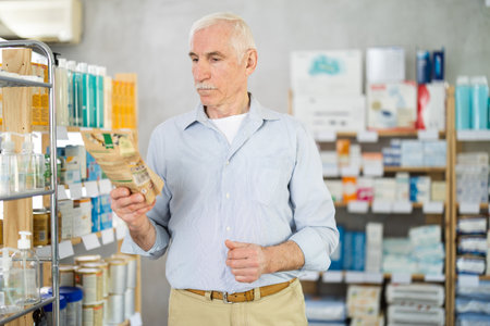 Elderly man chooses supplements at pharmacyの写真素材