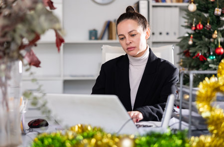 Portrait of successful business woman with New Years tinsel and Christmas tree in officeの写真素材