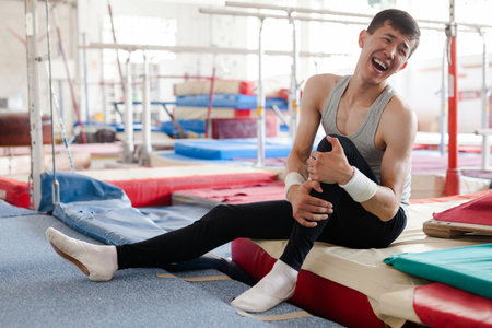 Injured male gymnast suffering from knee pain after bad landing
