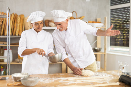 Elderly man and woman kneading and whipping dough