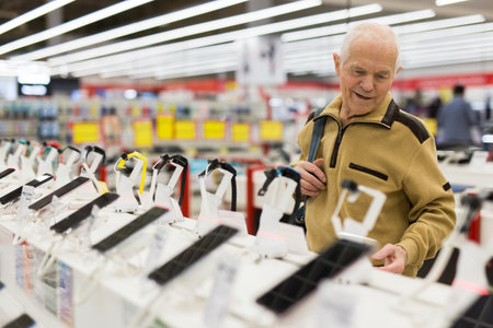 elderly man examines smart watch in showroom of electronics storeの写真素材
