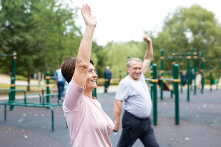Sports pensioners do a warm-up on outdoor sports ground