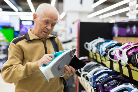 senor man pensioner buying iron in showroom of electrical appliance storeの写真素材