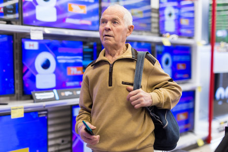 elderly man choosing TV in showroom of electronics storeの写真素材