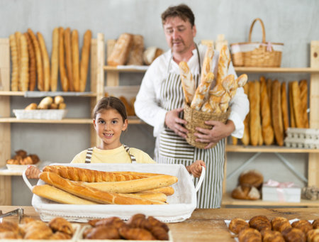 Father and little daughter - selling bread and various baguettesの写真素材