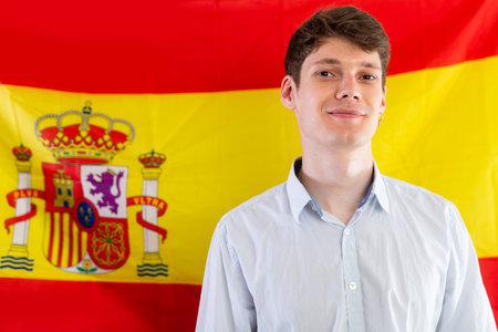 Portrait of positive student against background of flag of Spain. Concept of relocation and immigrationの写真素材