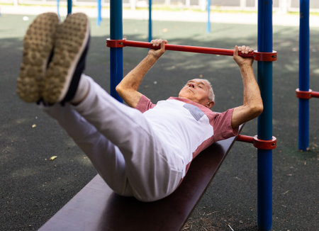 Old man doing leg raise exercise outdoors