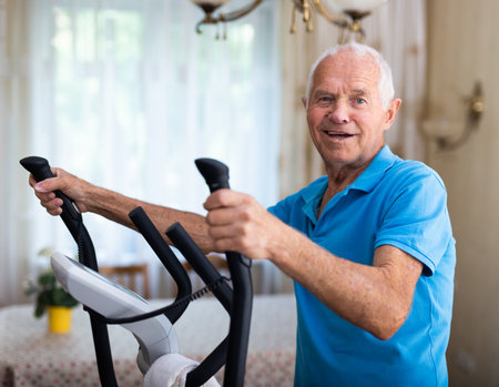 Fit senior man at home doing cardio work out on an elliptical machineの写真素材
