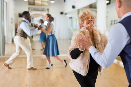 Mature woman learning to dance lindy hop with younger manの写真素材