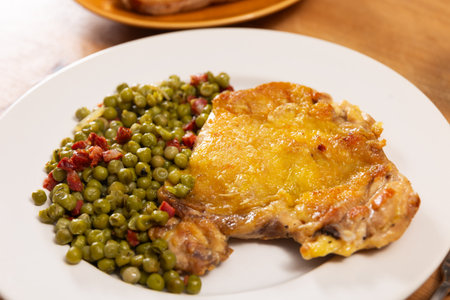 Delicious crispy chicken with peas as a side dish on a plateの写真素材