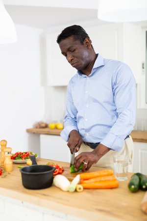 Man prepares a vegetable salad in the kitchenの写真素材