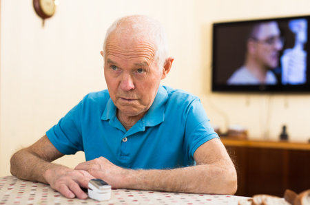 Worried elderly man measuring himself oxygen saturation at home