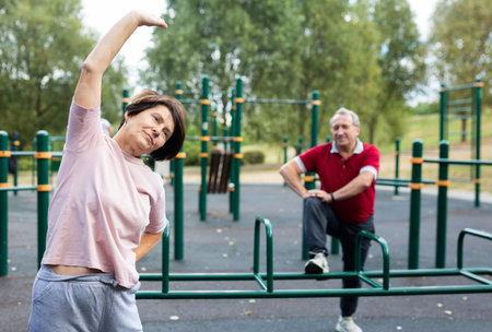 elderly woman doing gymnastics on an outdoor sports ground