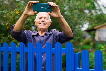 Grandfather takes selfie in front of his country house in villageの写真素材