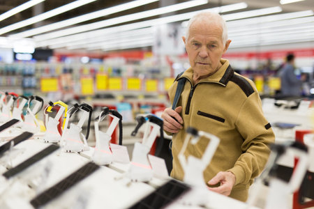 elderly man examines smart watch in showroom of electronics storeの写真素材