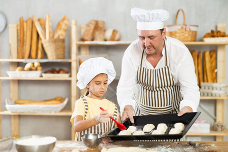 Daughter helps father baker to make pastries, lubricate croissants with loosened egg