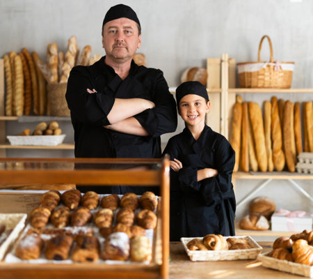 Father baker poses with his daughter in black chef uniformの写真素材