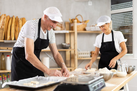 Elderly man and woman make and fold pieces of dough