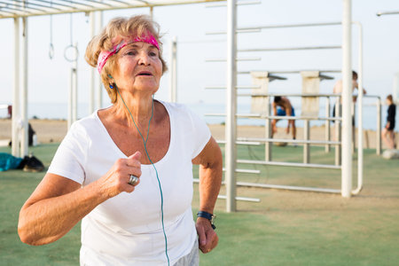 elderly woman runs outside doing sportsの写真素材