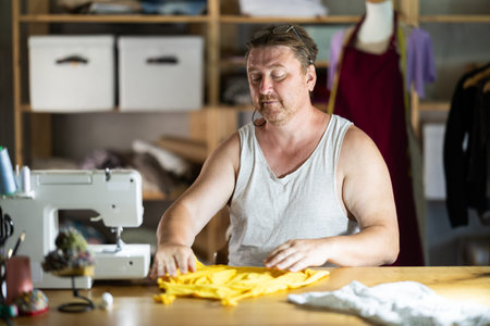 Man seamstress sewing manufactures childrens clothing