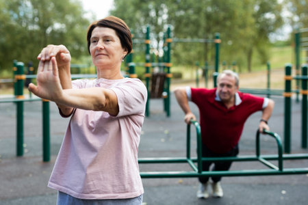 Healthy lifestyle in retirement - an elderly woman does a workout on the sports ground in park.