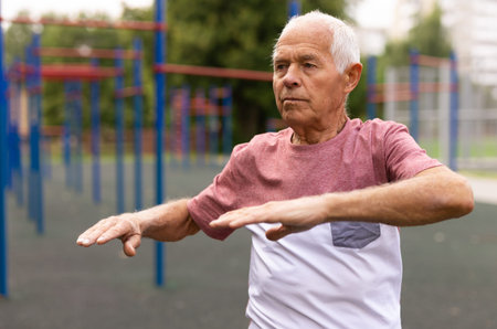 Elderly man doing fitness exercises outdoors