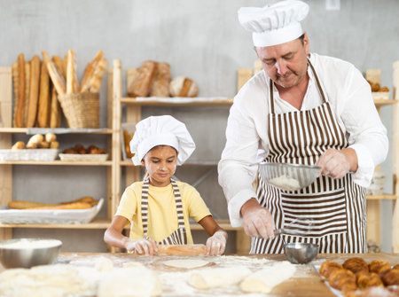 Bakers dad teaches daughter niece to work with dough, using rolling pin