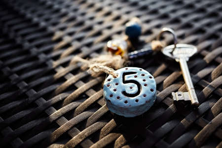 Authentic keychain on a straw table with a room number carved on itの写真素材