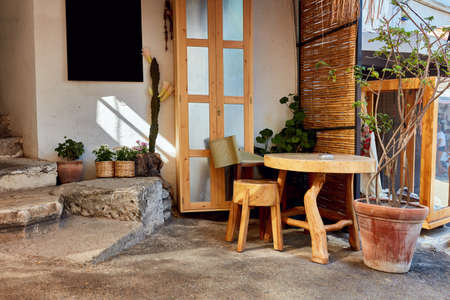 cute outdoor street cafe with small wooden table and stool. Black empty signboard on the wall.