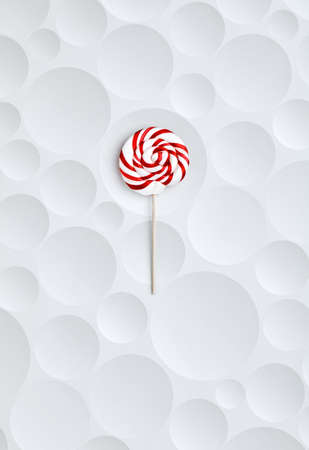 Delicious red striped and spiral shaped lollypop on white and bubble textured backgroundの写真素材