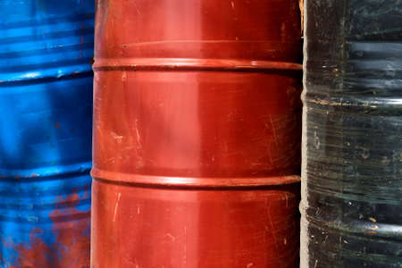 close-up shot of three old, scratched and rusty colorful barrelsの写真素材