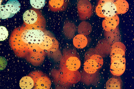 Raindrops on a window with blurred background of vibrant colors of city lightsの写真素材
