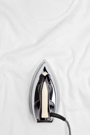 Retro iron ironing on a white wrinkled t-shirt. Top down vertical view.の写真素材