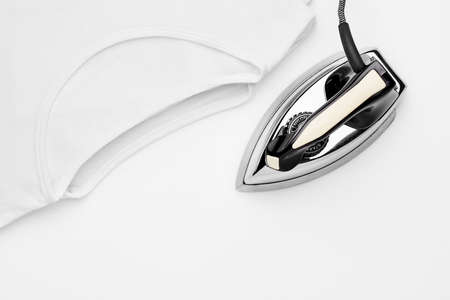 Retro iron and white t-shirts on white background. Concept of ironing.の写真素材