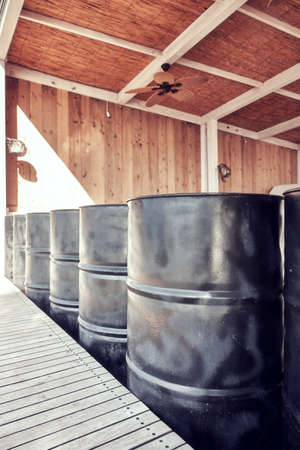 Black metal oil barrels in an outdoor storage space.
