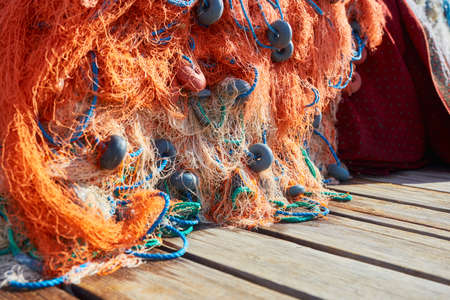 Pile of orange fishing net with blue rope and floats on the dock. Close up.の写真素材